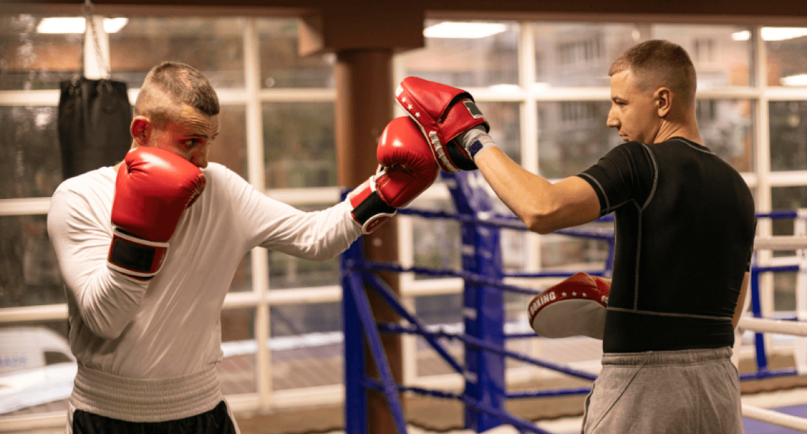 A boxer practising with a trainer in a boxing ring